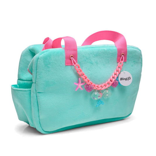 A blue beach tote with pink straps, featuring a decorative chain with charms, designed for seashell shopping.