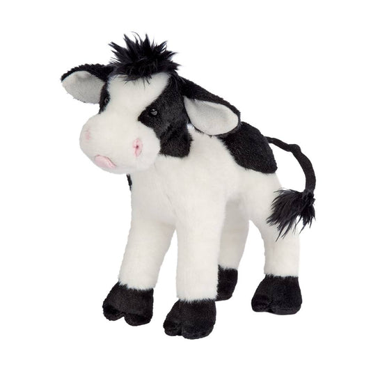 A plush toy resembling a baby cow with black and white spots, a pink tongue, and black hooves. The toy has a soft coat and shaggy black fur accents on the head and tail.