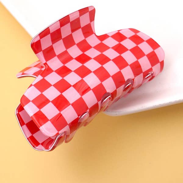 A red and white checkered heart-shaped hair claw clip on a yellow background