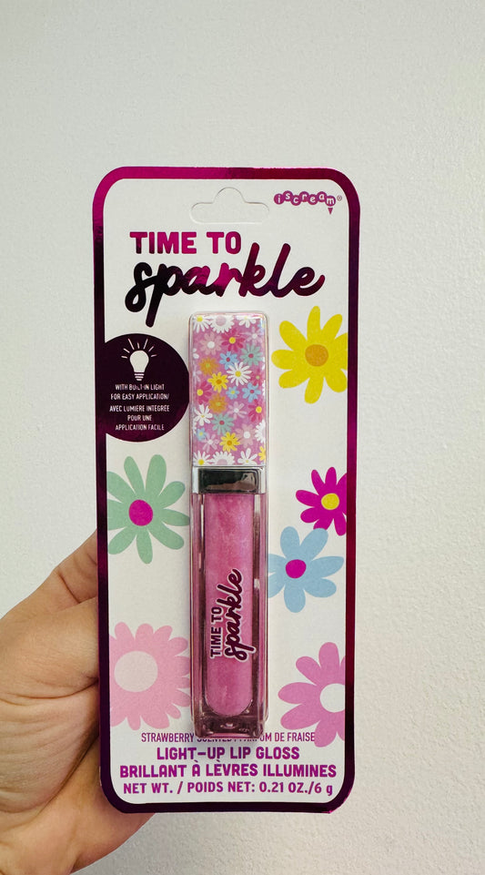 A packaged Time To Sparkle Light Up Lip Gloss in pink color with floral design on the packaging.