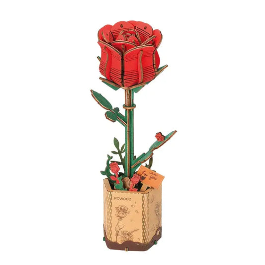 A completed 3D wooden puzzle model of a red rose with green leaves, mounted on a brown base that resembles a paper with a watermark 'ROBOTIME'.