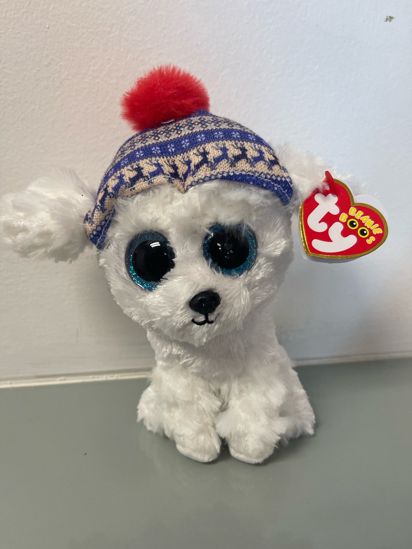 White beany boo plush toy dog with blue glitter eyes and a winter hat