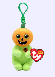 A plush toy resembling a pumpkin with a jack-o'-lantern face, green body, and a clip on top, with the Ty brand tag attached.