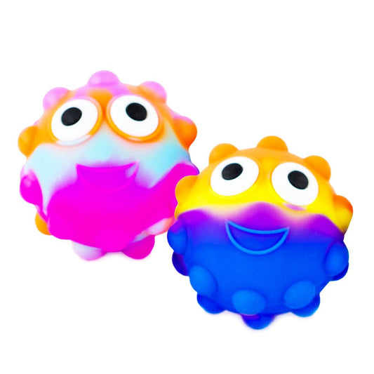 Two plastic toy balls with colorful tutti frutti patterns and cute eyes popping out from the top.