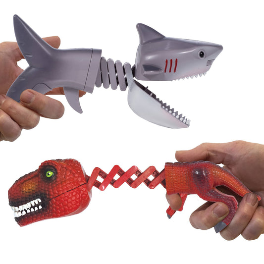 A toy shark and a toy dinosaur with extendable chomping jaws held in hands.