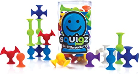 A collection of multicolored suction construction pieces, known as Squigz, displayed alongside their packaging which features a happy face.